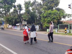 Jaga Keselamatan Kanit Binmas Polsek Bayah Polres Lebak Bantu Menyebrang Jalan Anak Sekolah