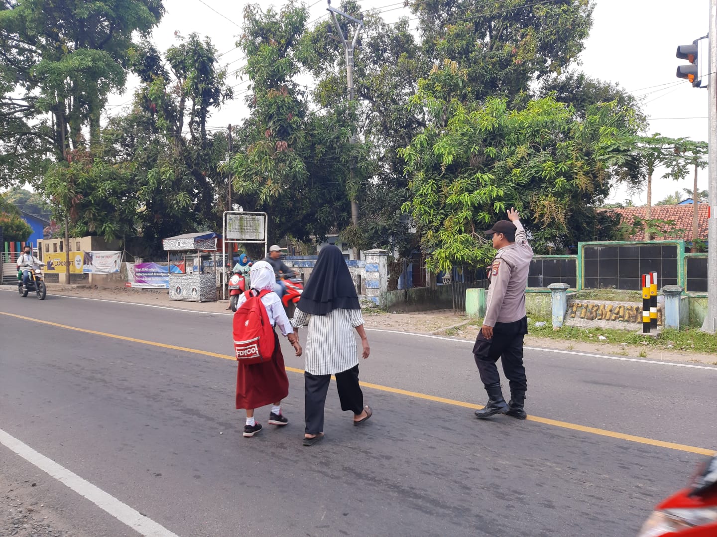 Jaga Keselamatan Kanit Binmas Polsek Bayah Polres Lebak Bantu Menyebrang Jalan Anak Sekolah