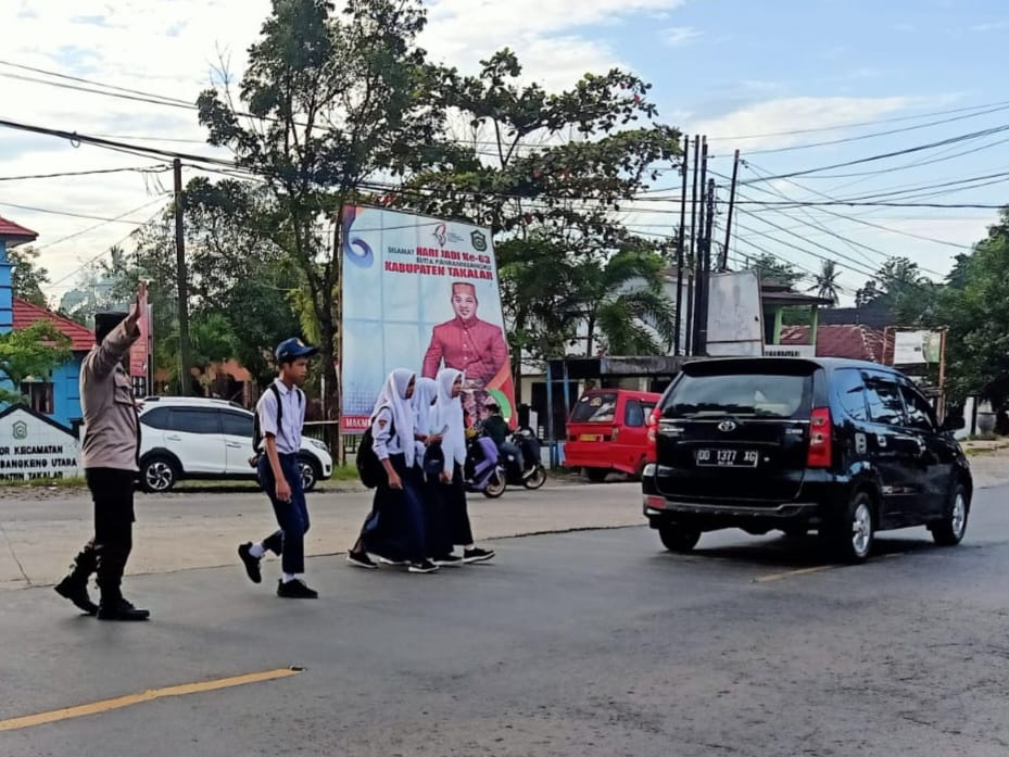 Hadir Ditengah Masyarakat, Polisi Polsek Polut Bantu Pelajar Menyeberang Jalan